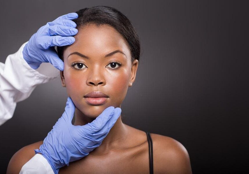 Woman receiving a facial examination from a professional with gloves.