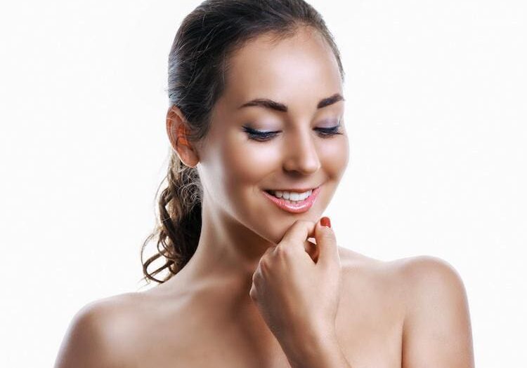 Smiling woman with smooth skin and a gentle touch on her chin.