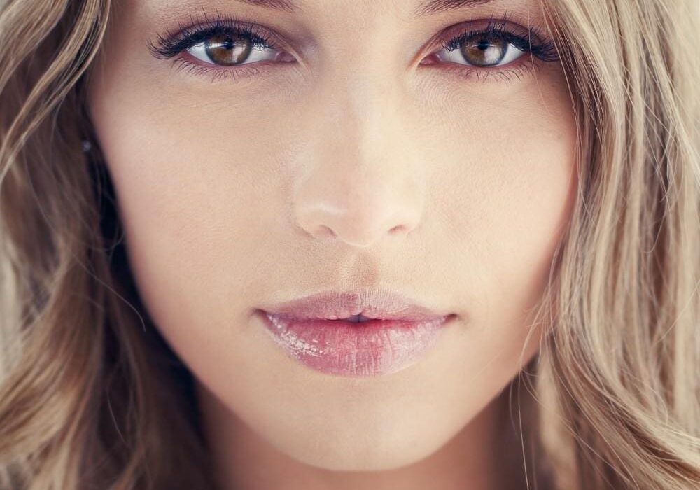 Close-up portrait of a young woman with blonde hair and natural makeup.