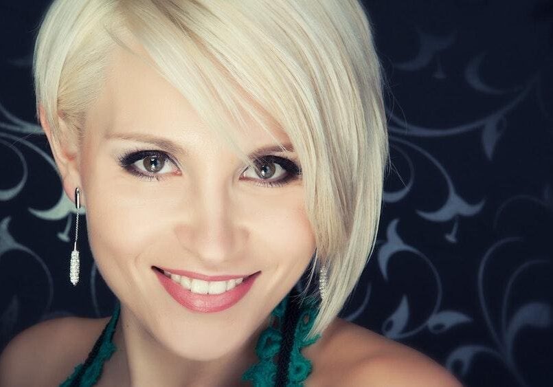 Smiling woman with short platinum blonde hair and bright eyes.