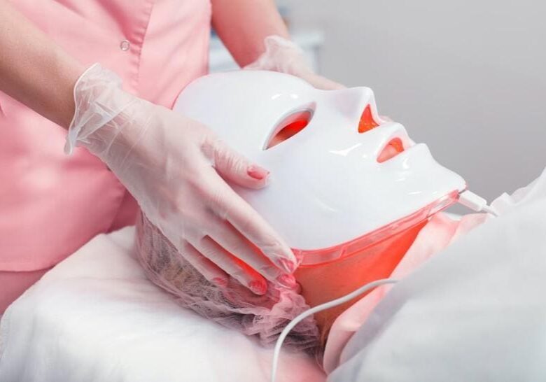 Person receiving a facial treatment with a LED light therapy mask.
