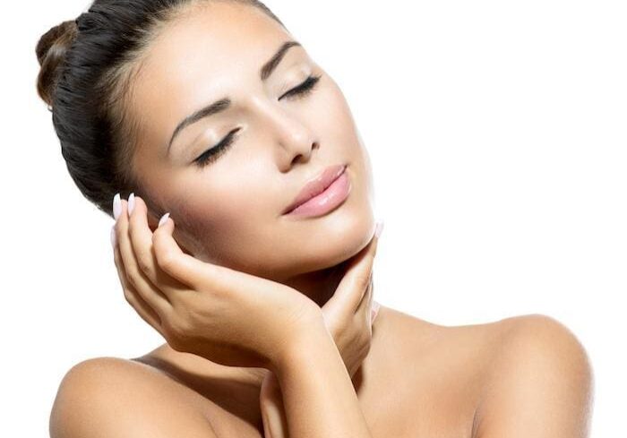 Woman with eyes closed, gently touching her face, radiating calm and beauty.