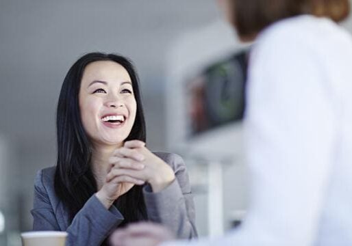 A woman smiling and engaged in conversation with another person.