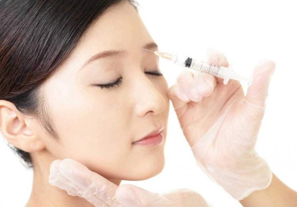 A woman receiving a cosmetic injection near her eye.
