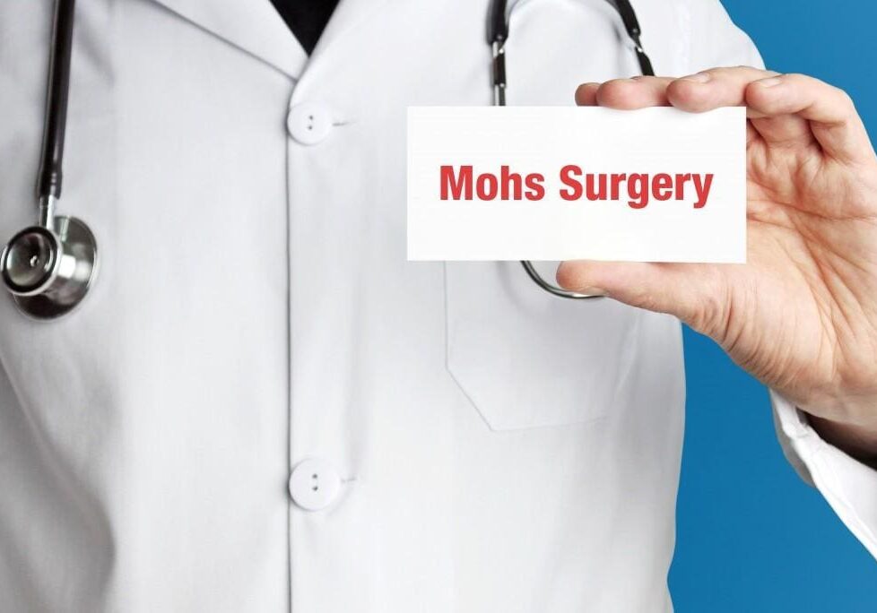 Doctor holding a card labeled Mohs Surgery.