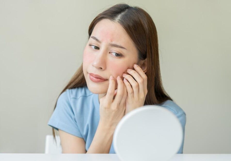 Woman examining her skin closely in the mirror.