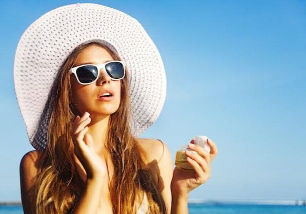 Woman in sunglasses and a white hat enjoying sunny beach weather.